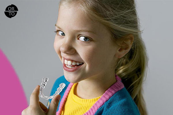 elinde şeffaf ortodontik plak olan küçük bir kız