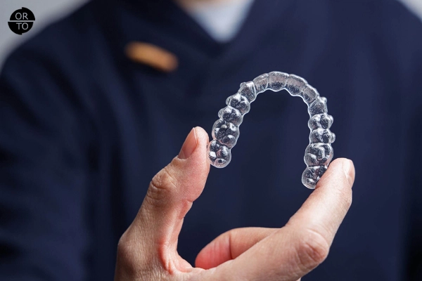 Şeffaf diş plaklarını (Invisalign aligner) elinde tutan kişi