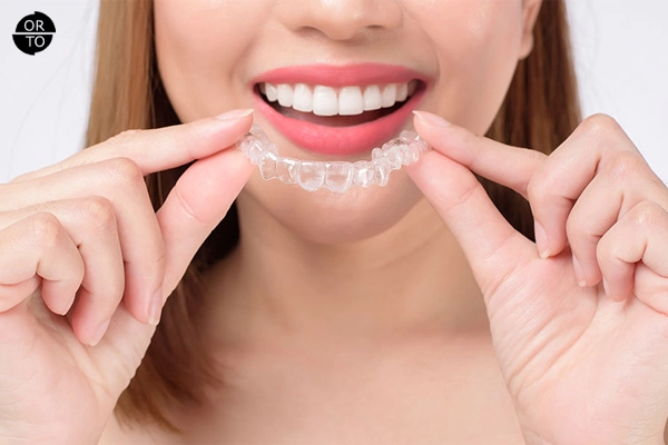 Şeffaf plak (Invisalign) tedavisi için plak takan gülümseyen kadın