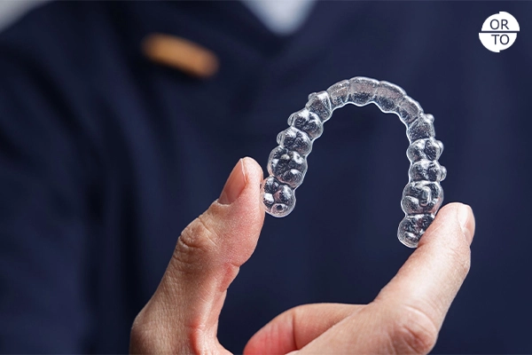 Bir kişinin elinde tuttuğu Invisalign şeffaf diş plağı (aligner)