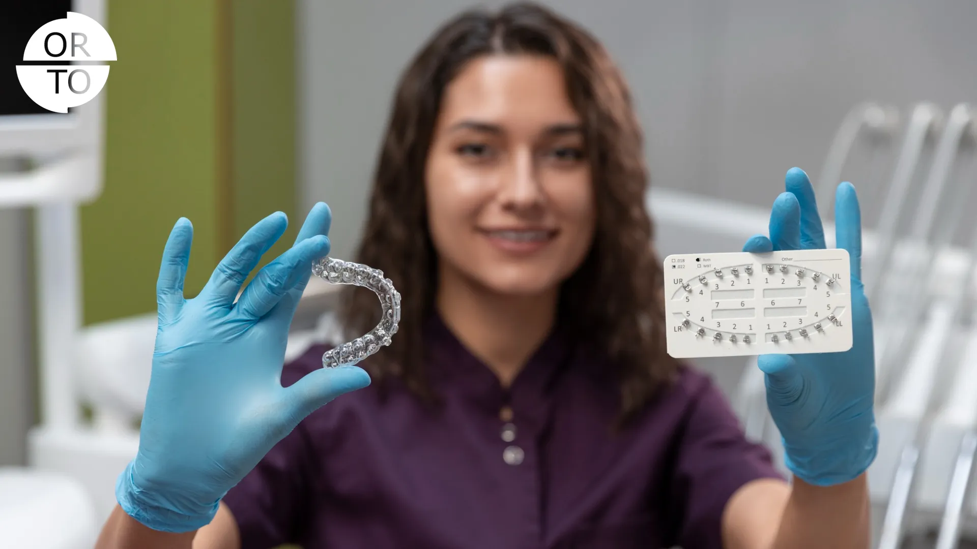 Ortodontist, elinde şeffaf plak ve braket ölçüm kartı tutuyor.